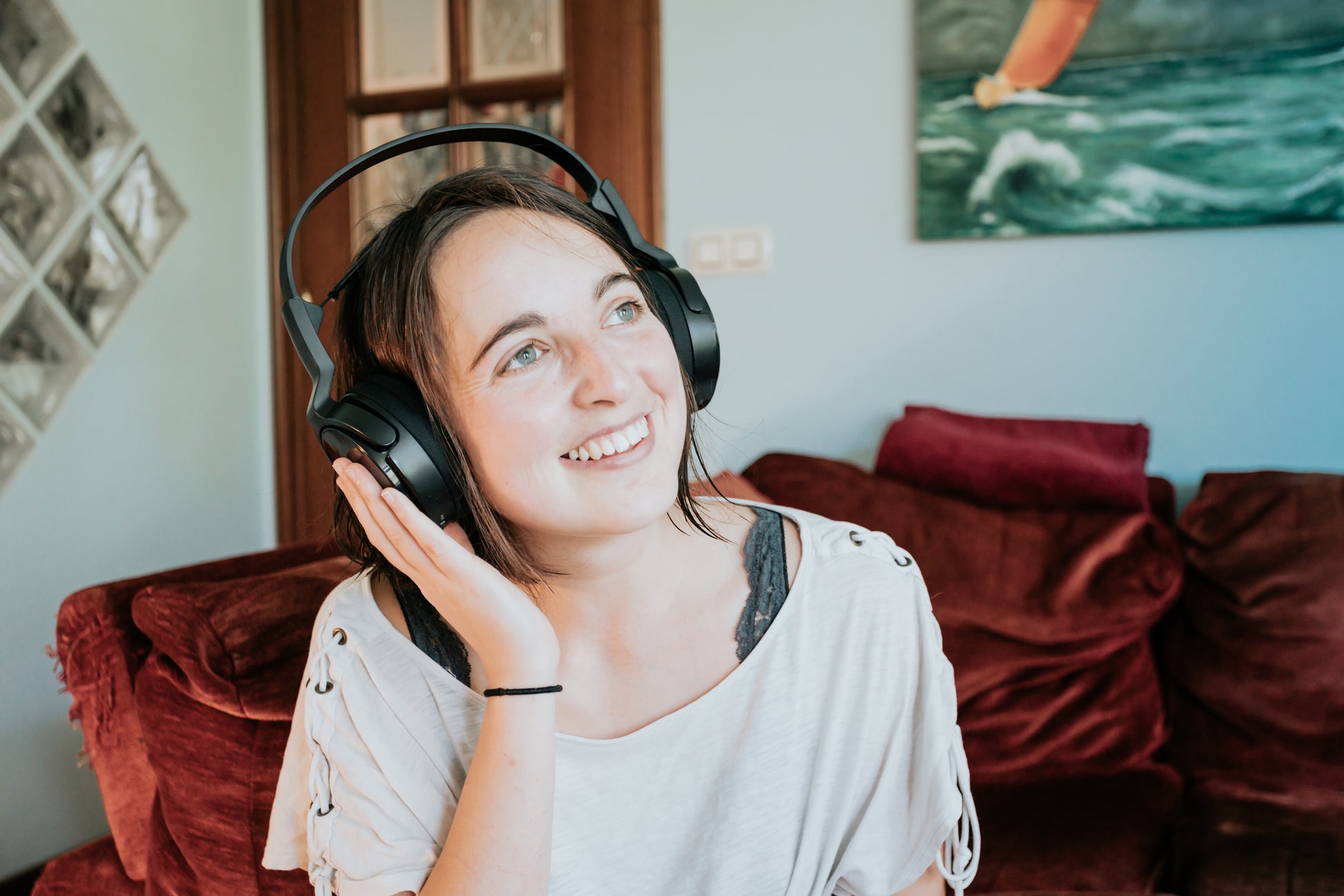 woman-wears-headphones-with-one-hand-up-smiling_1950x